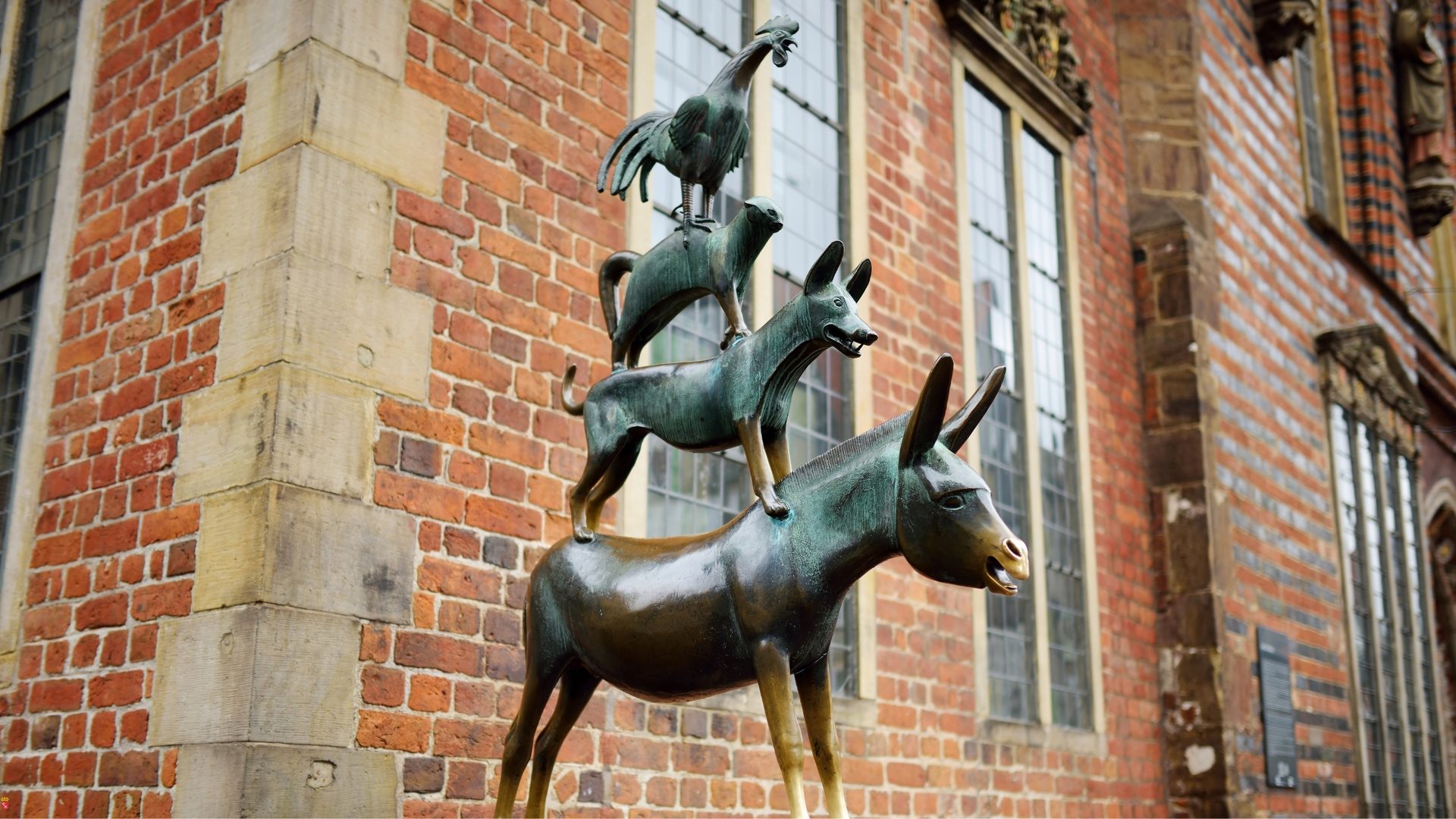 Bronzestatue der Bremer Stadtmusikanten vor der Backsteinfassade des Rathauses