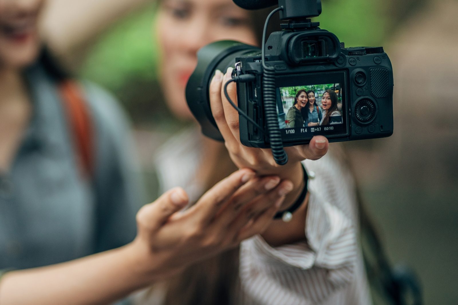 Junge Frau filmt mit Kamera und aufgestecktem Mikrofon einen Clip für Social Media