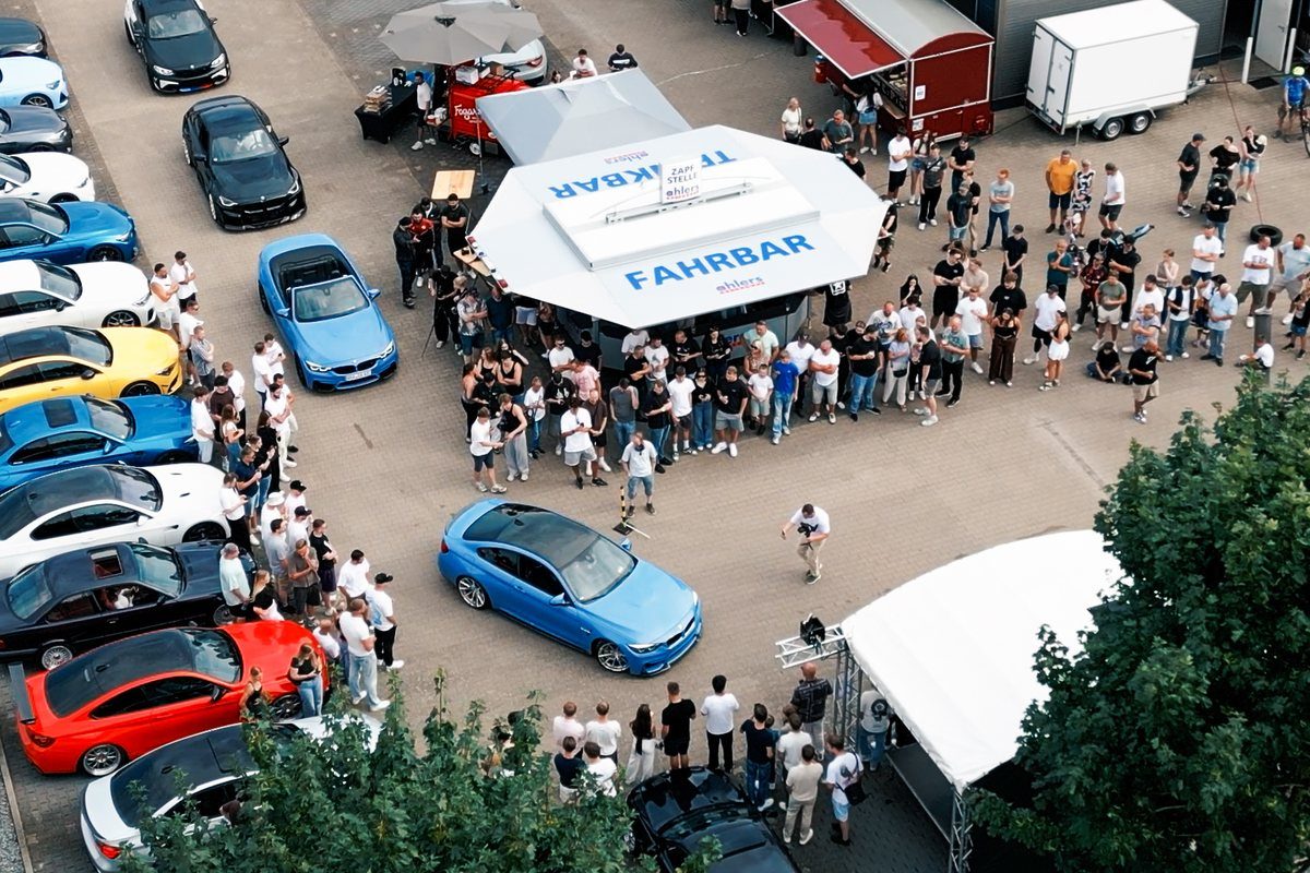 Drohnenaufnahme eines Sommerfests mit Sportwagen und Besuchern in Bremen