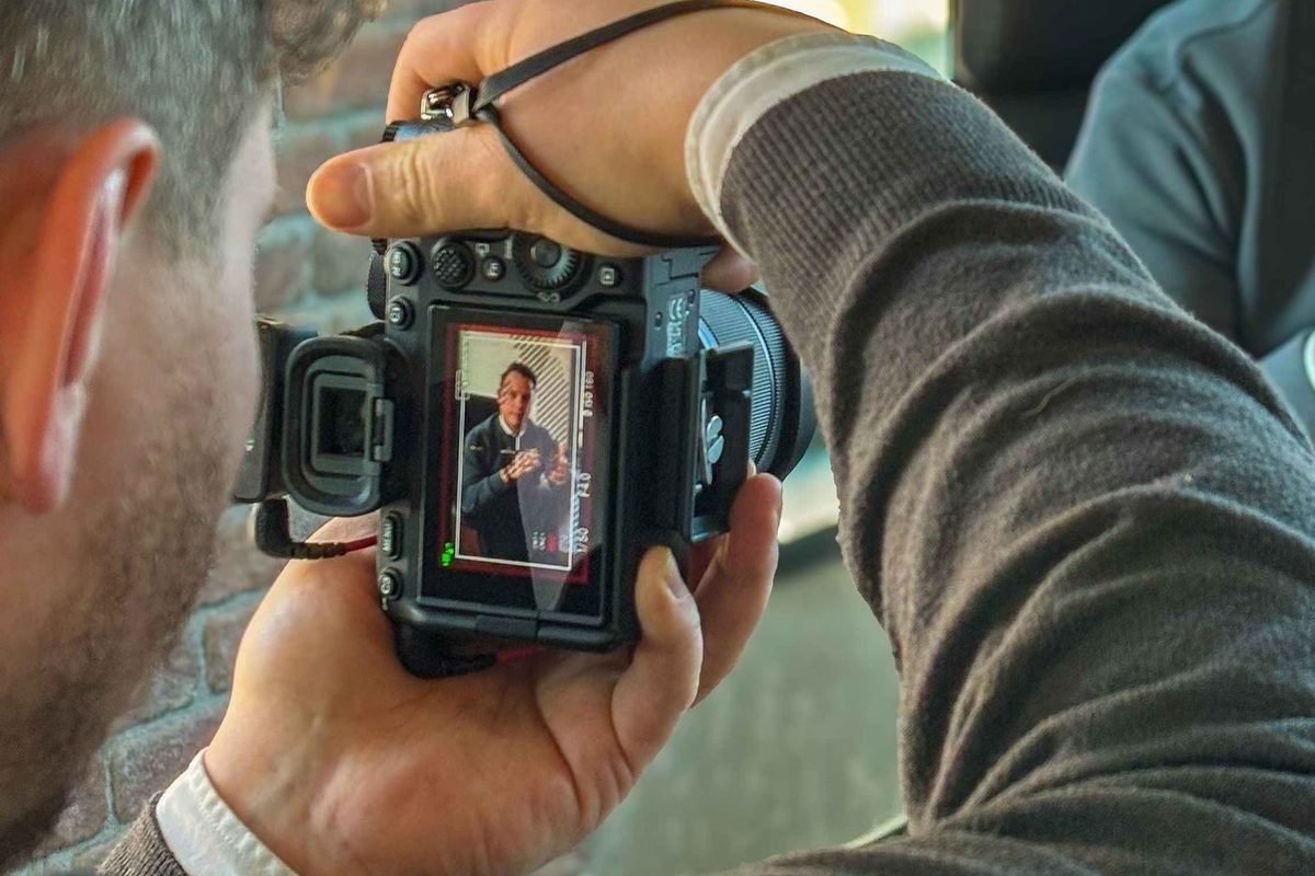 Fotograf prüft eine Porträtaufnahme auf dem Kameradisplay am Fenster