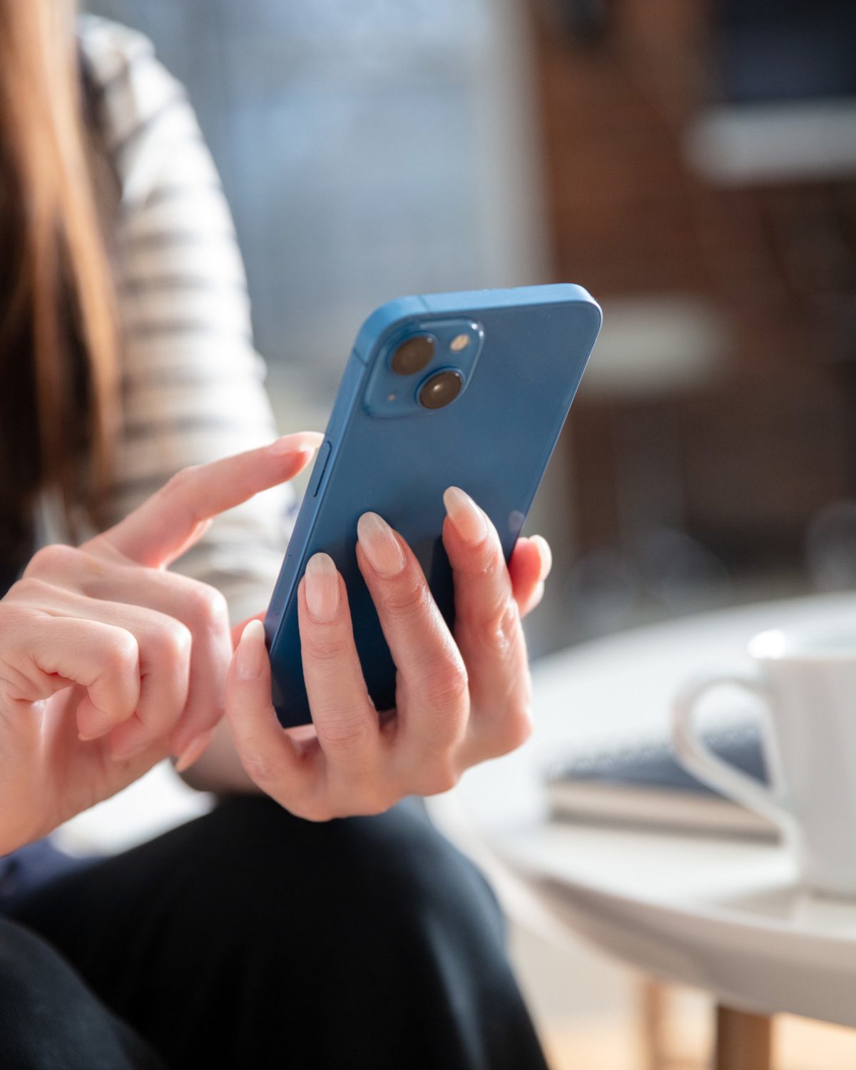 Frau mit Smartphone im Café, Beispiel für lokale Social-Media-Reichweite