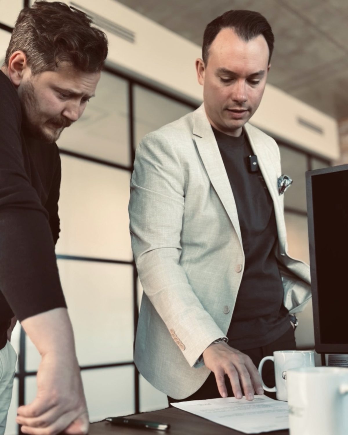 Zwei Männer besprechen Unterlagen am Tisch beim Videodreh