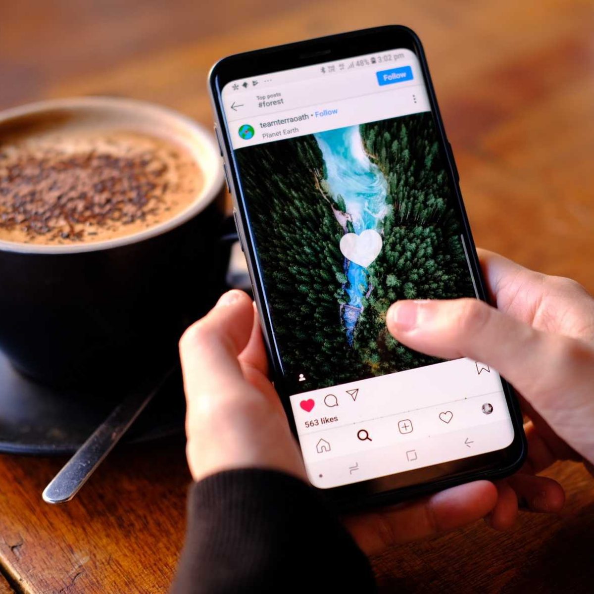 Smartphone mit geöffnetem Instagram-Reel auf einem Tisch im Café
