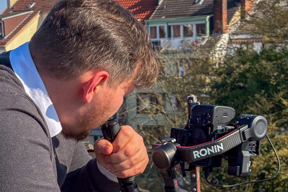 Kameramann von Green Media Bremen filmt mit einer Gimbal-Kamera auf einem Dach über Bremen