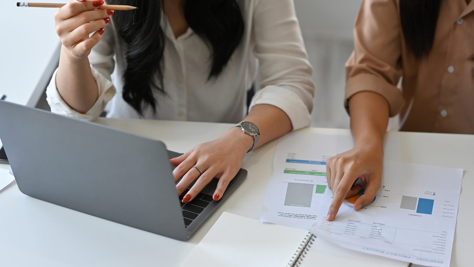 Zwei Personen planen am Laptop mit Notizen und Farbmustern die Inhalte einer Recruiting-Kampagne
