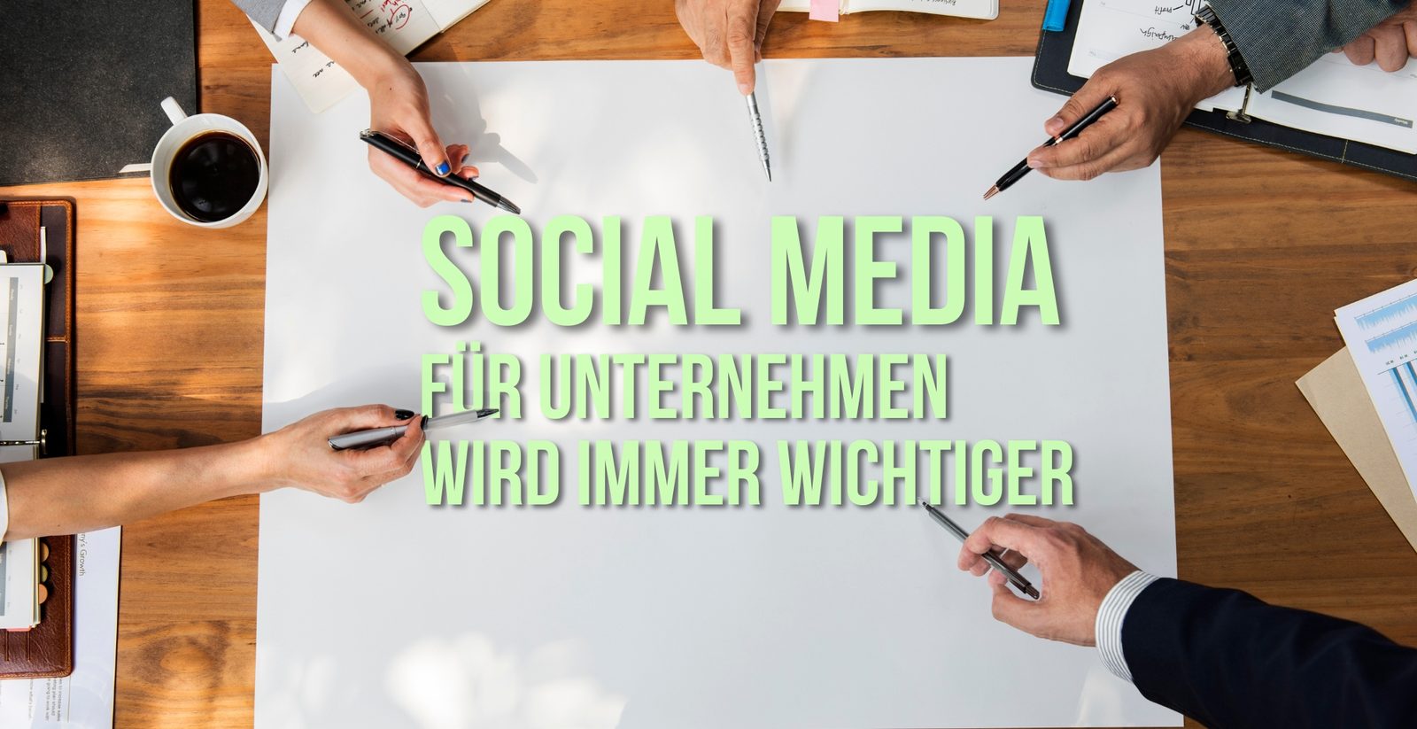 Hände mit Stiften über einem Plan mit dem Schriftzug „Social Media für Unternehmen wird immer wichtiger“