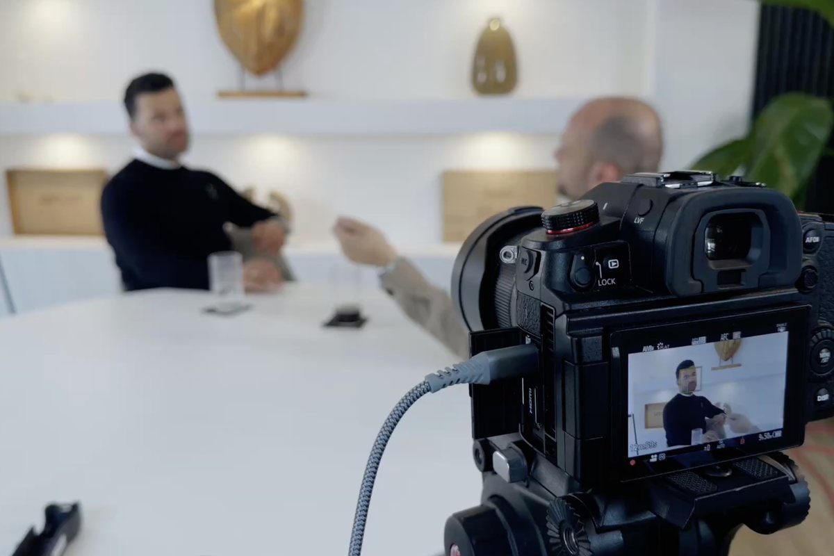 Videointerview mit zwei Geschäftspartnern am Konferenztisch, Kamera im Vordergrund