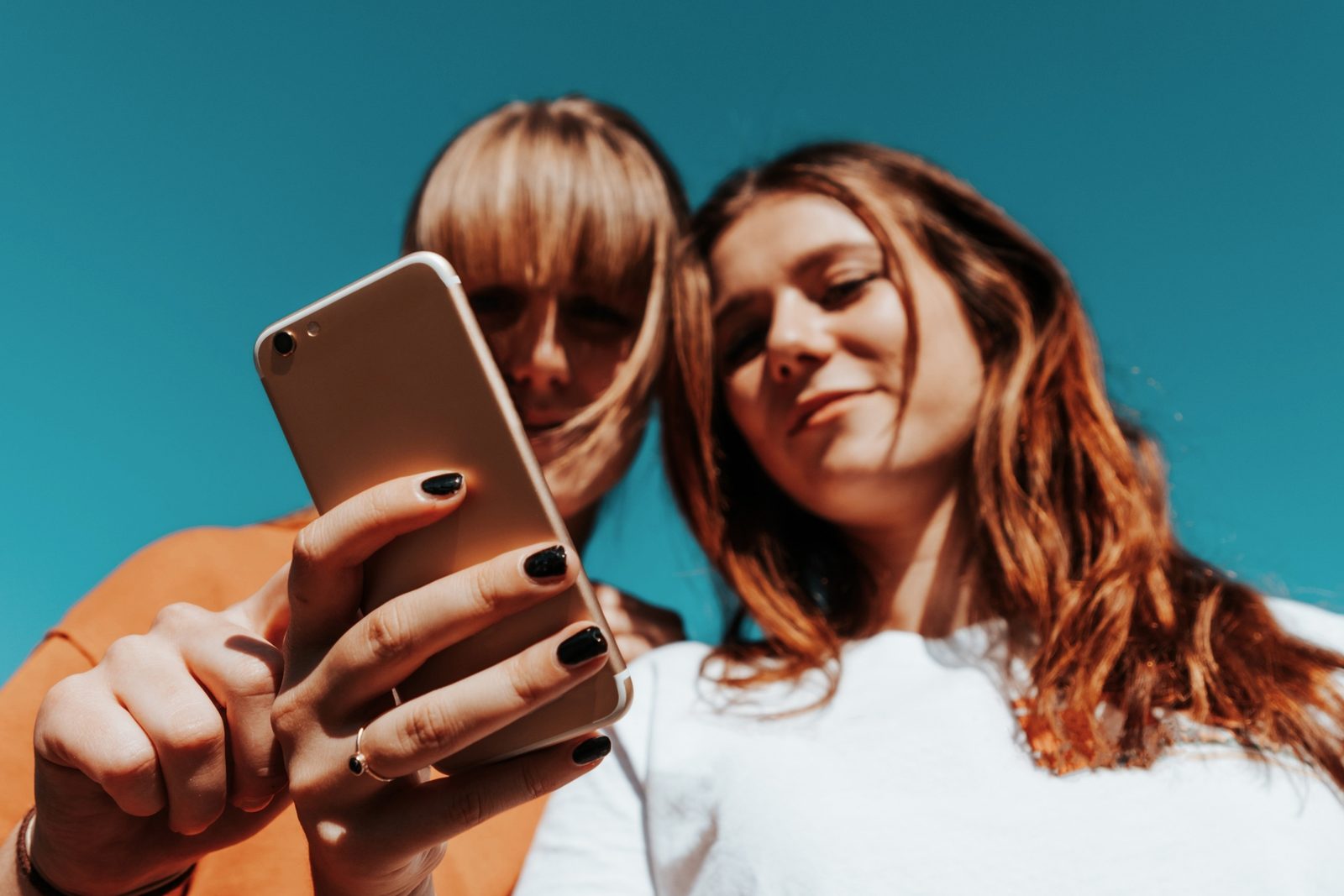 Zwei junge Frauen schauen gemeinsam lachend auf ein Smartphone